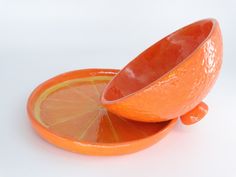 an orange is sitting in a bowl on the floor next to it's slice