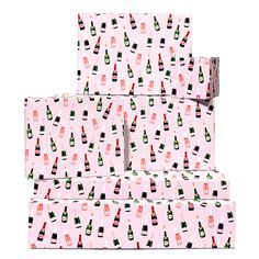 pink wrapping paper with bottles and glasses on it, stacked up in the shape of boxes