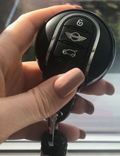 a hand holding a car key in front of a window