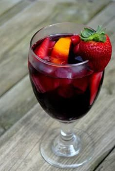 a glass filled with fruit sitting on top of a wooden table