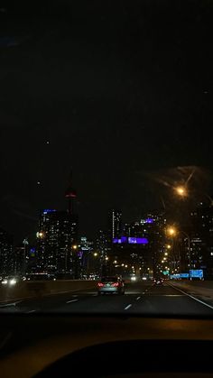 the city lights shine brightly in the dark night sky as seen from inside a car