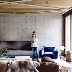 a woman standing in a living room next to a blue couch and chair with fur on it