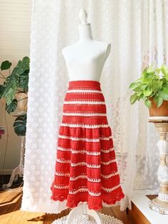 a red and white crocheted skirt sitting on top of a mannequin