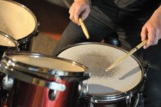 a man is playing the drums in front of his drum set while another person sits behind him