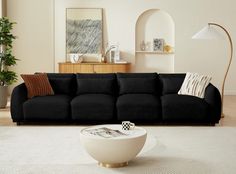 a black couch sitting in a living room next to a white rug and table with two lamps on it