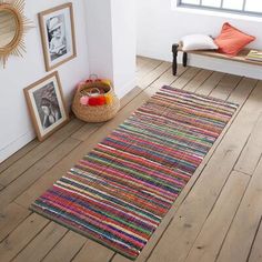 a room with wood flooring and white walls has a colorful rug on the floor