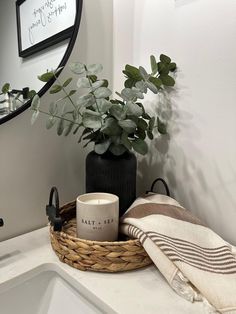 a bathroom sink with a plant and coffee cup on the counter top next to it