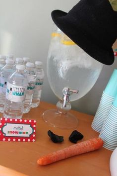 a table topped with lots of water bottles next to a carrot and a plastic cup