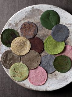 a white plate topped with lots of different colored rocks and leafy green leaves on top of it