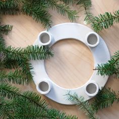 a white circular object sitting on top of a wooden table next to pine cones and branches