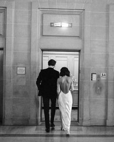 a man and woman in formal wear are walking into an elevator with their back to the camera