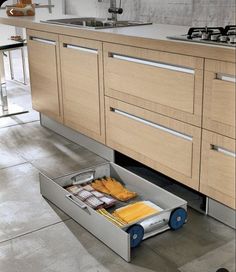 an open drawer in the middle of a kitchen with some food inside and on the floor