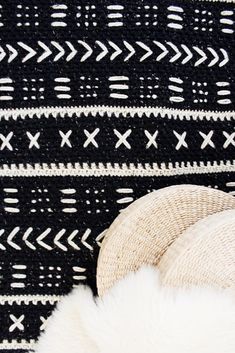 a white hat sitting on top of a black and white blanket next to a stuffed animal