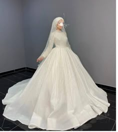 a woman in a white wedding dress standing next to a mannequin wearing a veil