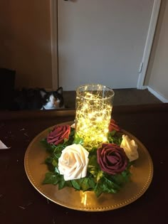 a plate that has some flowers on it with a candle in the middle and a cat behind it