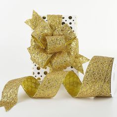 a roll of gold foiled ribbon with polka dots on it and a white box