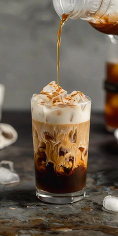 an iced coffee drink being poured into a glass with ice and caramel on top