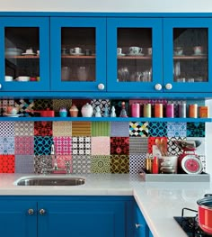 a kitchen with blue cabinets and colorful tile backsplash