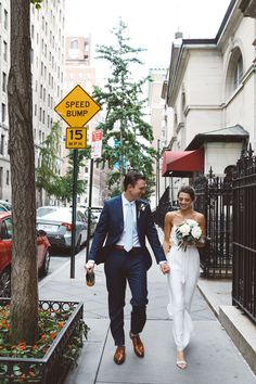 a bride and groom walking down the sidewalk in front of a speed bump street sign