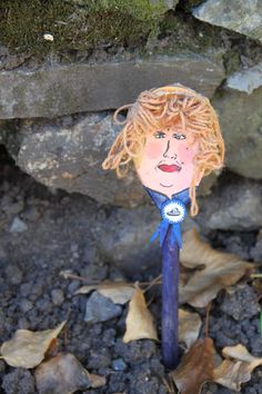 a blue toothbrush with a drawing of a woman's face on it sitting in the dirt