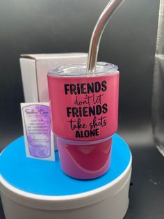 a pink cup with a straw sticking out of it sitting on top of a blue stand