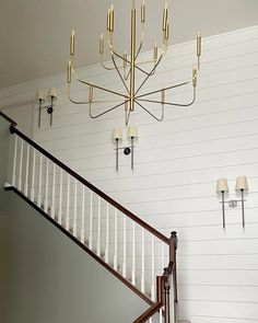 a chandelier hanging from the ceiling in a room with white walls and wood floors