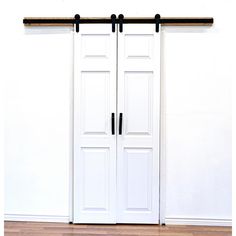 two white doors with black handles are open on a wooden floor in front of a white wall