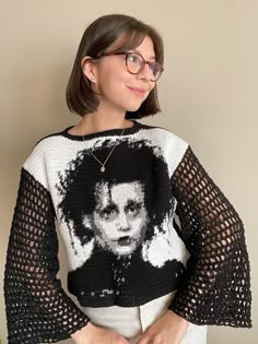 a woman wearing glasses and a knitted sweater with an image of a man on it