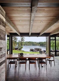 a dining room table and chairs in front of a large window looking out onto the lake