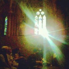 sunlight shining through the stained glass windows in an old church with people sitting on chairs