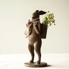 a statue of a rabbit holding a basket with flowers