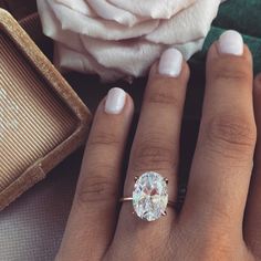 a woman's hand with a ring on it and a rose in the background