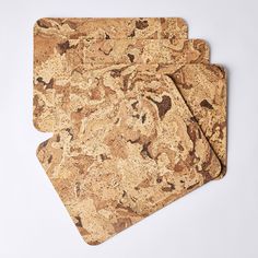 two cork placemats sitting on top of each other in front of a white background