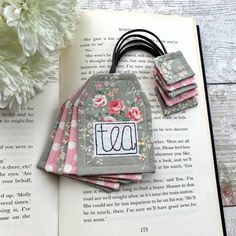 an open book with flowers on it and some kind of tags attached to the pages