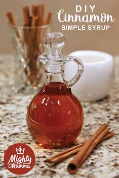 homemade cinnamon syrup in a glass carafe with cinnamon sticks next to it on a marble countertop