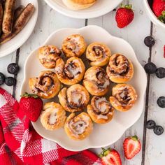 a white plate topped with cinnamon rolls next to strawberries