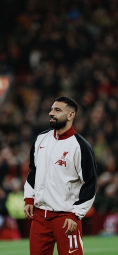 a man standing on top of a soccer field wearing red and white pants with his mouth open