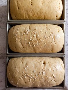 three loafs of bread sitting on top of each other in pans next to each other