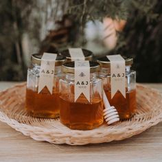 honey jars with labels on them sitting on a wicker tray next to a tree