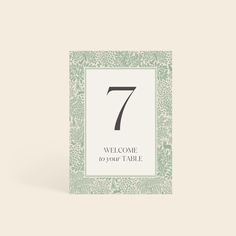 a green and white table number card with the number seven in it's center