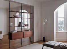 a living room with an arched window and bookshelf next to a bench in front of a large window