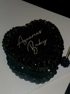 a black cake with writing on it sitting on a white table next to a knife