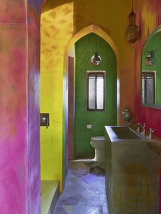 the bathroom is painted bright colors and has an arched doorway that leads to another room