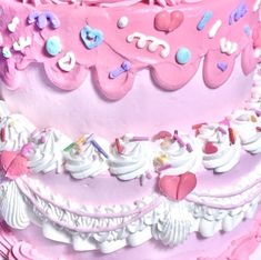 there is a pink cake with hearts and other decorations on the top layer, decorated with white icing