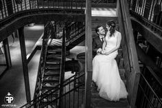 a bride and groom sitting on the stairs at their wedding reception in black and white