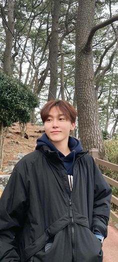 a young man standing in front of some trees