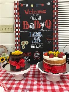 two cakes sitting on top of plates with sunflowers in the middle and a welcome sign behind them