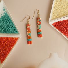 two pairs of beaded earrings sitting next to each other on top of a table