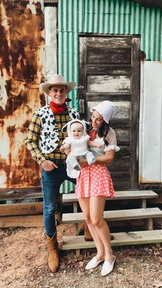 a man and woman in cowboy outfits holding a baby