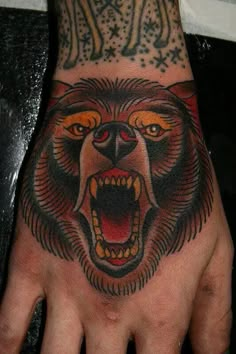 a man's hand with a bear tattoo on it and an evil looking face